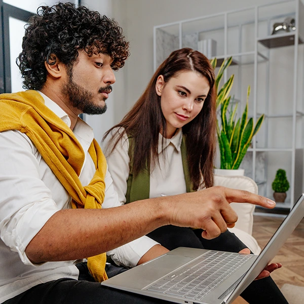 Hombre y mujer trabajando juntos en una computadora portátil, revisando información y colaborando en un entorno de oficina